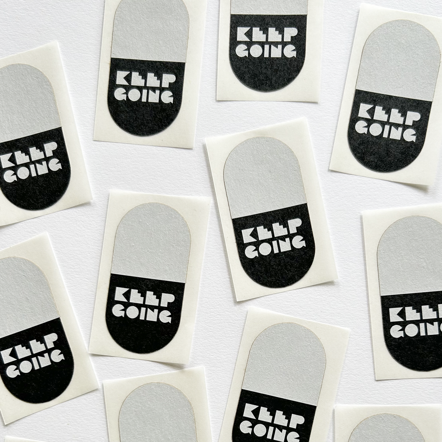 Black and white pill-shaped stickers that state KEEP GOING
