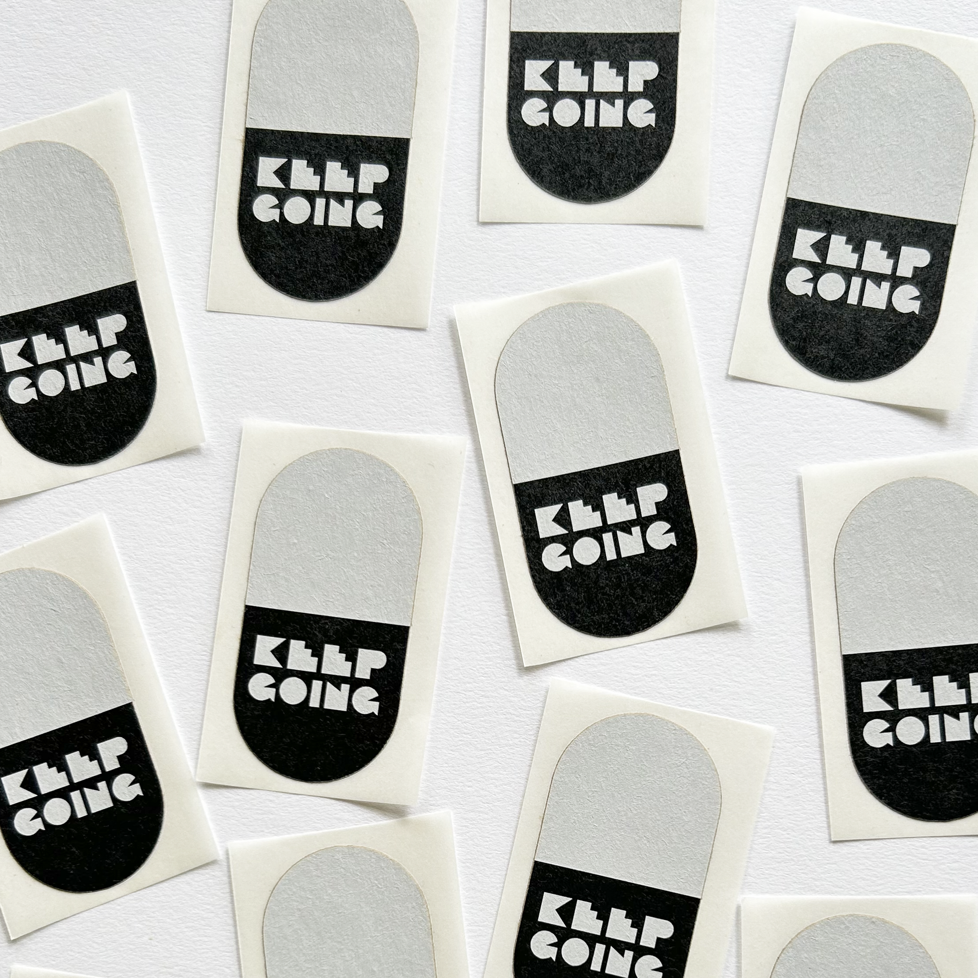 Black and white pill-shaped stickers that state KEEP GOING